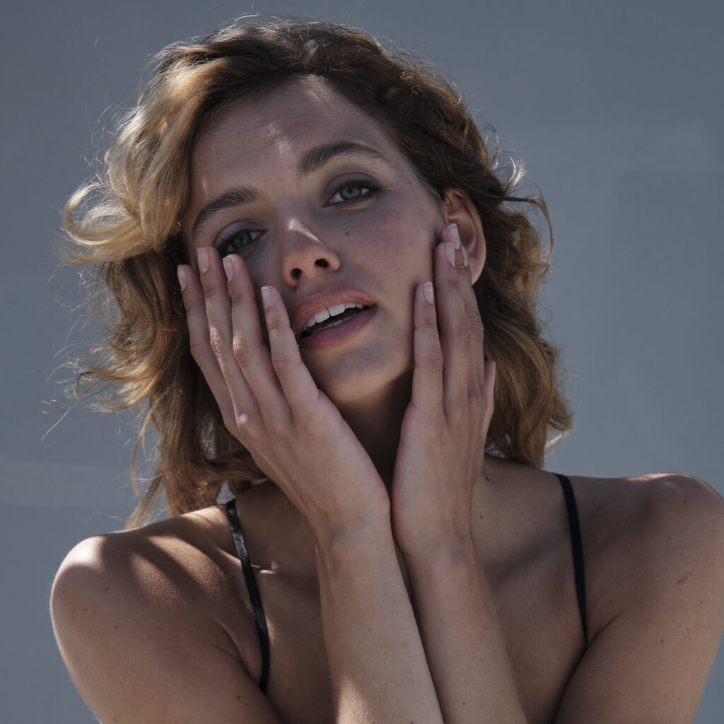 Cineastisches Farbfoto Fine Art Portrait einer Frau mit ausdrucksstarker Handgestik und natürlichem Lichtspiel