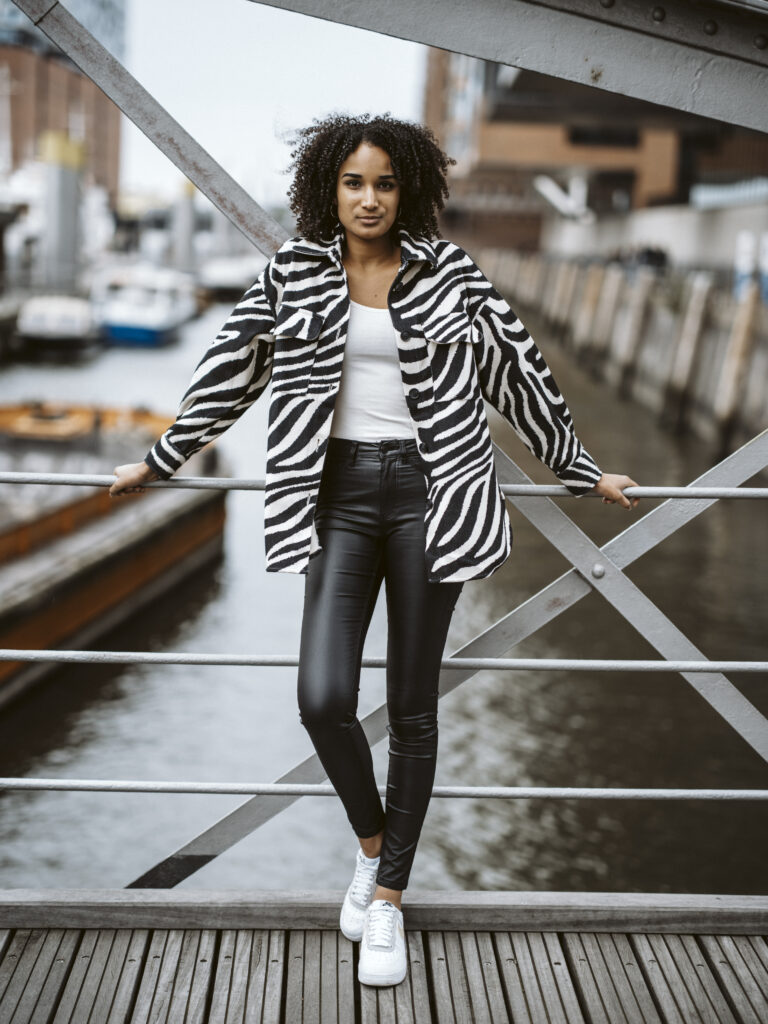 Model Clara im Zebra-Muster-Hemd lehnt an einer Brücke über einem Fleet in Hamburg
