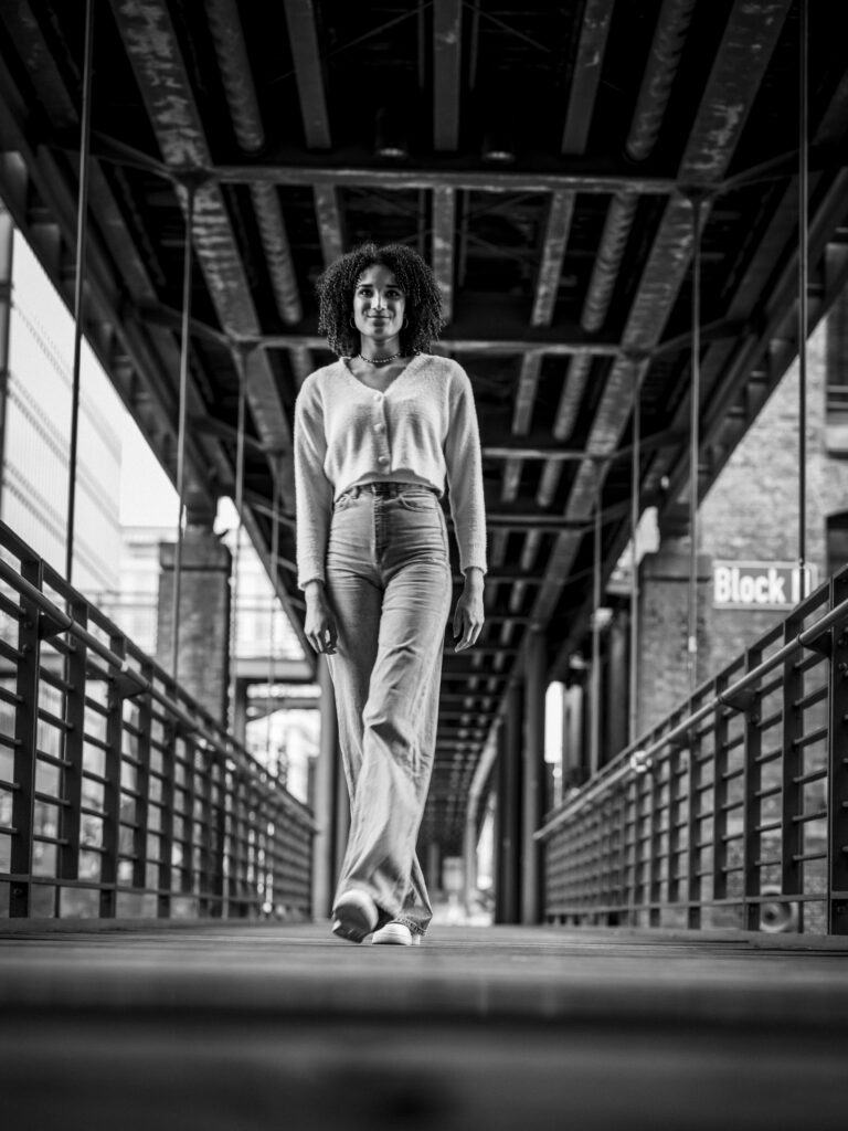 Schwarz-Weiß-Ganzkörperaufnahme eines Models unter einer Stahlträgerbrücke in Hamburg