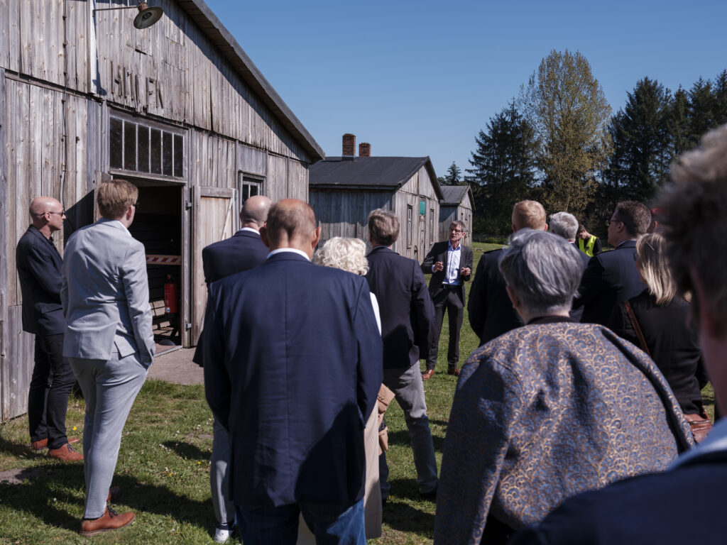 Besuchergruppe bei einer Führung zwischen historischen Holzbaracken der Gedenkstätte Lager Sandbostel.