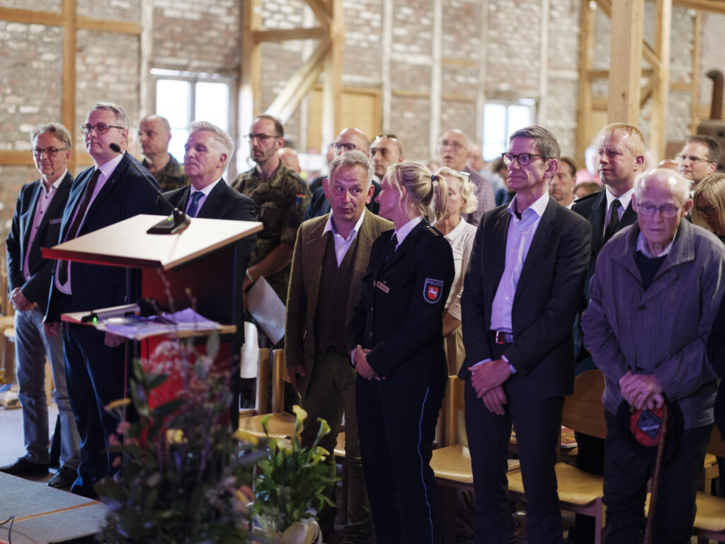 Gäste und Vertreter verschiedener Institutionen stehen während einer Veranstaltung in einem historischen Gebäude in Sandbostel.