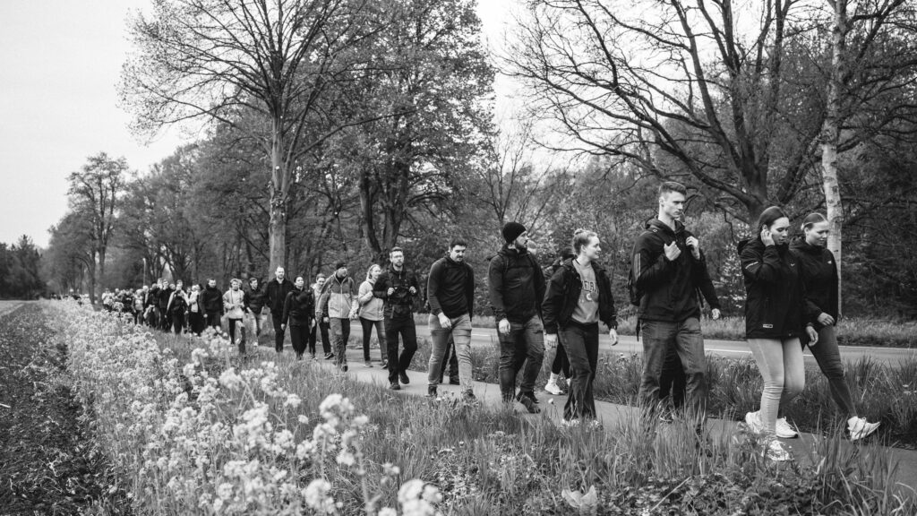 Teilnehmende des Gedenkmarsches ziehen in einer langen Gruppe durch eine Straße.