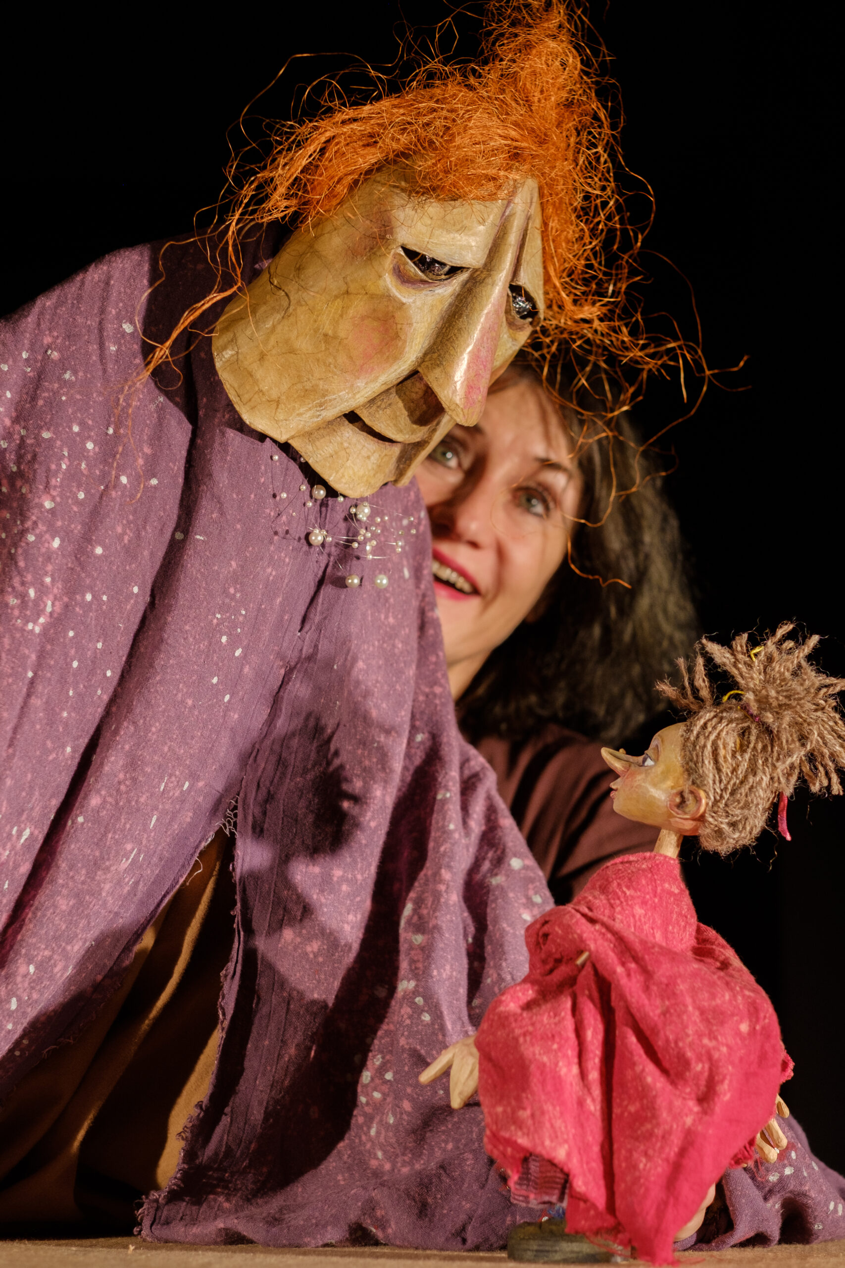 Figurenspielerin Heike Klockmeier zwischen einer großen Hexenfigur und einer kleinen Figur in rotem Kleid in „Kleine Hexe Siebenreich“.