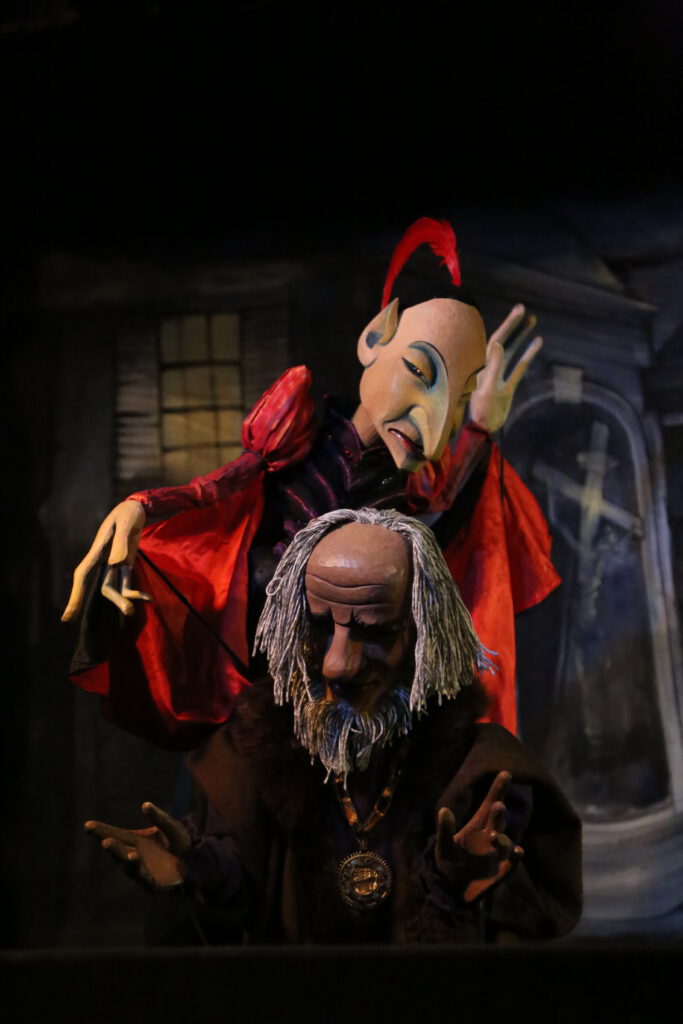 Faust und Mephisto - Zwei ausdrucksstarke Marionetten in einer dunklen Szene aus „Doktor Faust“ des Hohenloher Figurentheaters, die obere Figur in leuchtend rotem Kostüm.