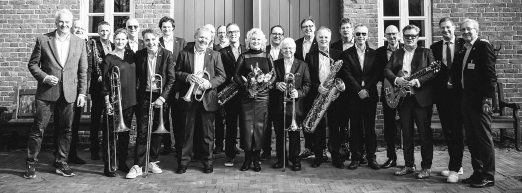 Gruppenfoto der International Rotary Bigband mit Instrumenten im Freien vor einer Backsteinwand.